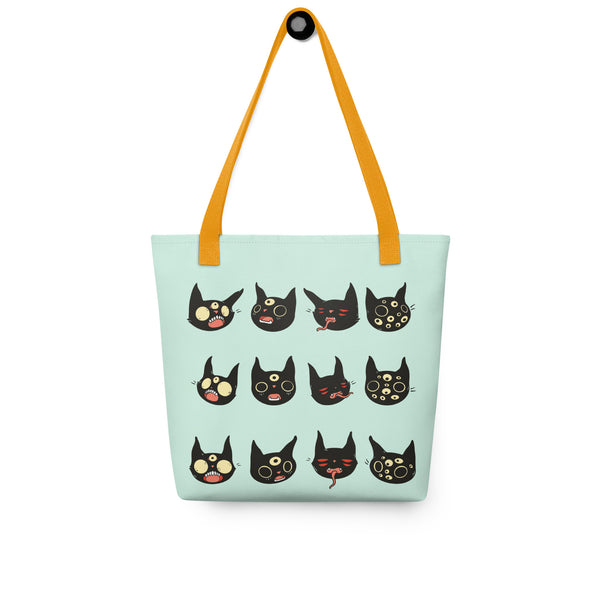 Spacious tote bag featuring hand-drawn black cat faces on a light mint background with orange handles.