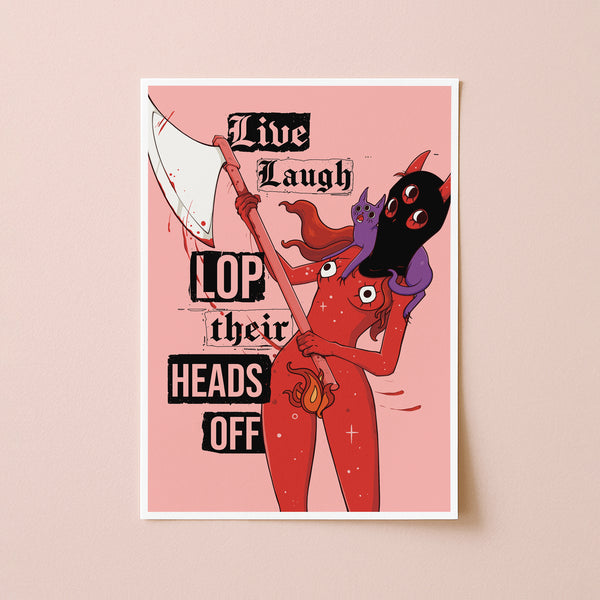 A vertical art print with a white border, featuring a stylized red devil character holding a scythe with a black cat on its shoulders, set against a pink background with the text 'Live Laugh LOP their HEADS OFF'. The print is displayed against a solid light beige wall.