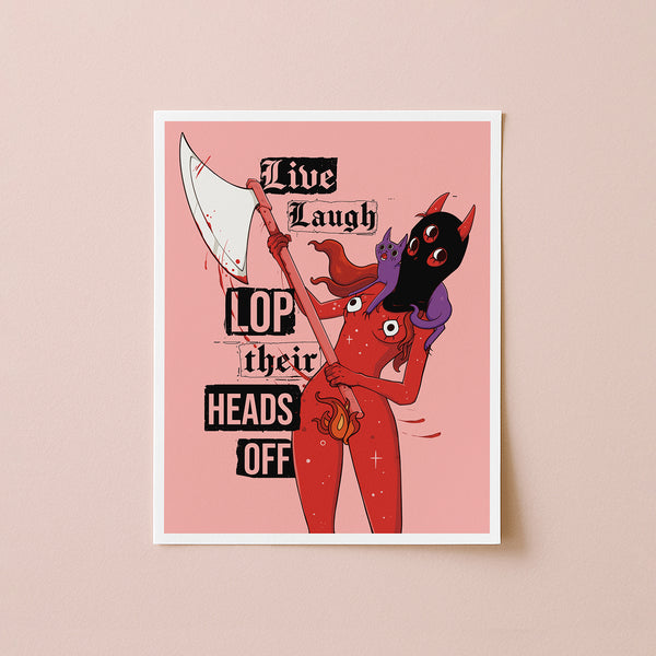 A framed art print featuring a red devil character holding a large scythe, with black text reading 'Live Laugh LOP their HEADS OFF' on a pink background, displayed against a beige wall.