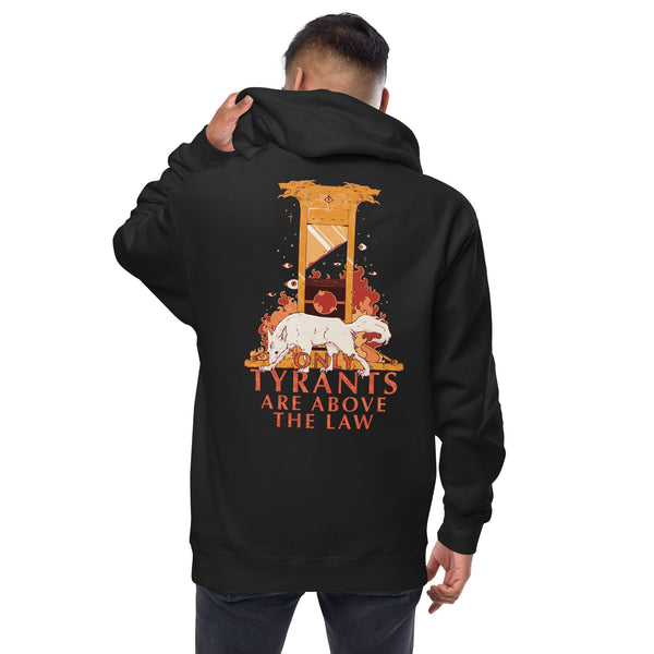 A man shown from the back wearing a black hoodie with a large graphic print on the back. The design features a guillotine, a white dog, and the text 'TYRANTS ARE ABOVE THE LAW' in orange and white.