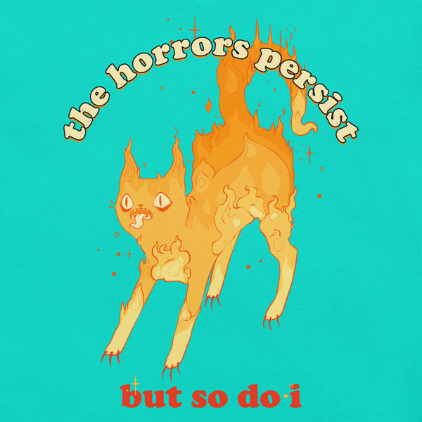 Fire cat illustration on unisex t-shirt with quote "the horrors persist but so do i" on vibrant turquoise background.