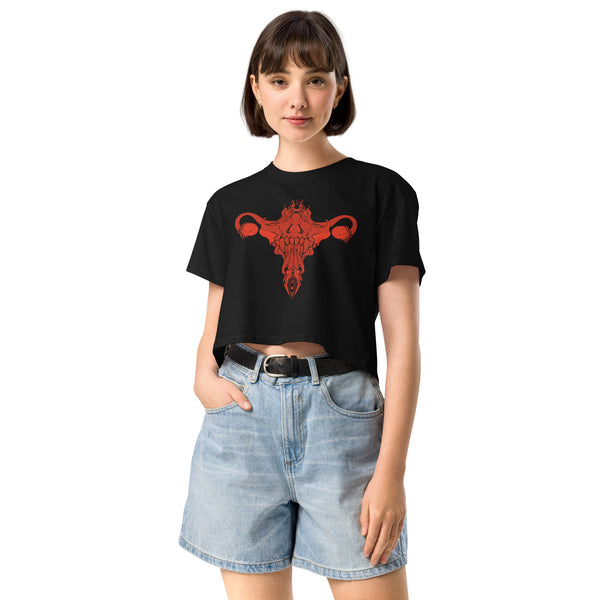 Woman wearing black Death Metal Uterus relaxed crop top with hand-drawn artwork, paired with denim shorts, featuring alt aesthetic.