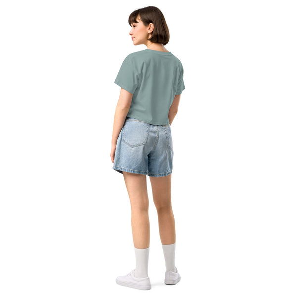 Model wearing a relaxed crop top with dropped shoulders, paired with denim shorts from a back view.