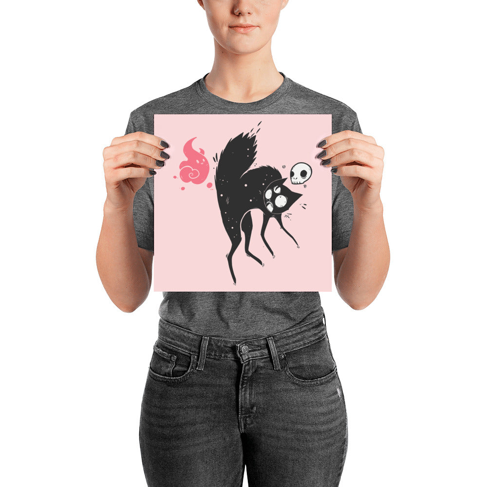 Person holding a Kuro black cat art print poster featuring a cat with a skull and ghost on a pink background.