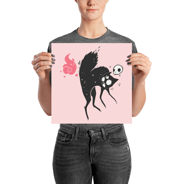 Matte art print of Kuro, a black cat with a skull and ghost friend, held by a person, showcasing unique character design.