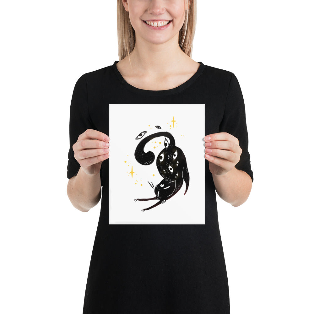 Woman holding a matte art print of a stretching black cat illustration with sparkles.