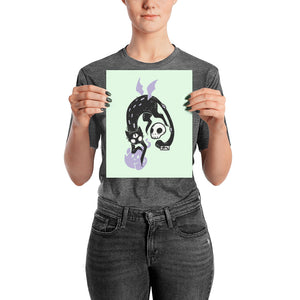 Matte art print of a black cat Kuro with a skull and ghost, held by a person against a mint background.
